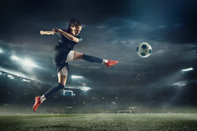 Young footballer with long hair kicking a ball 
