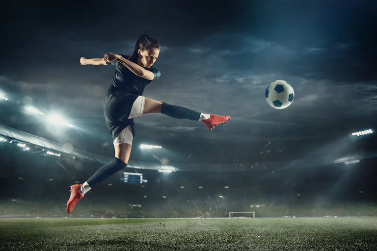 Young footballer with long hair kicking a ball
