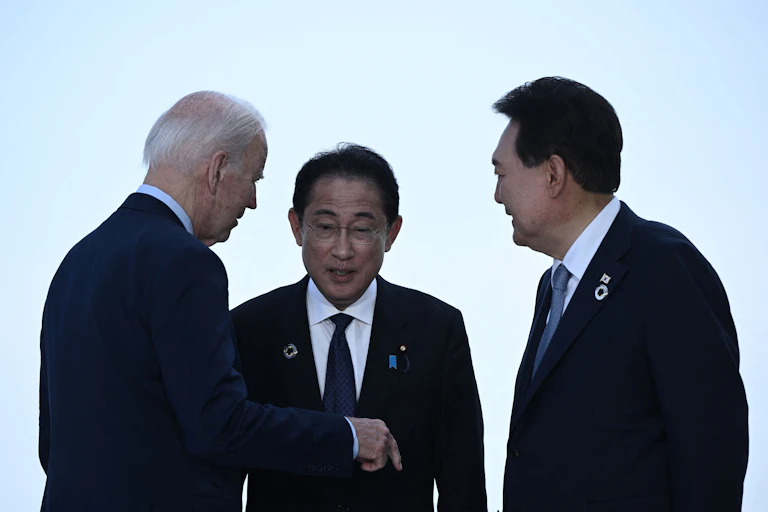 Three men in suits chat.