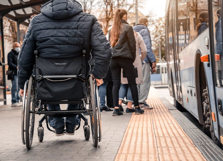 A person in a wheelchair waiting to board a city bus