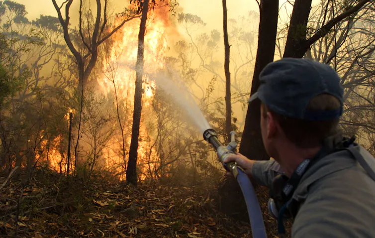 person points water hose to fire