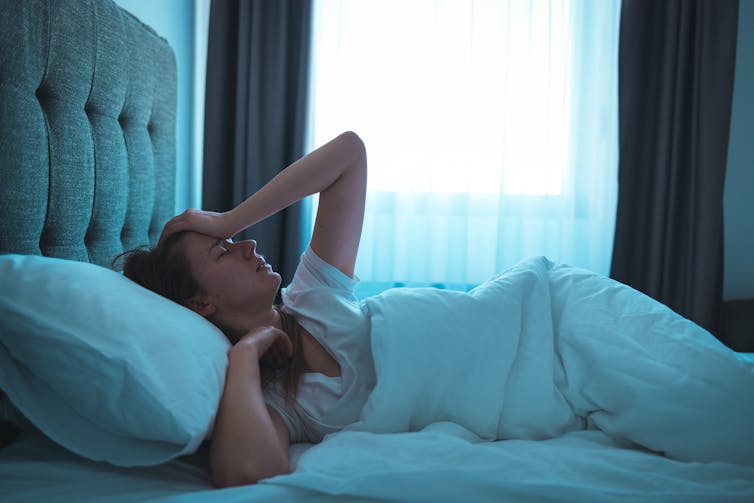 Woman lays in bed, comfortable