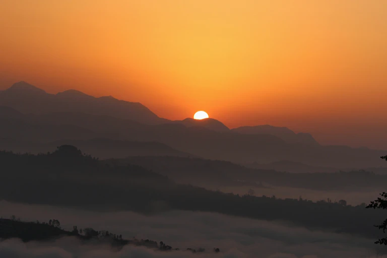 Sun peeking over misty mountain tops