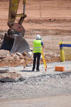 homme en gilet jaune réalisant une mesure sur un chantier