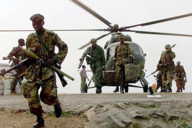 Des hommes armés en uniforme militaire débarquent d'un hélicoptère