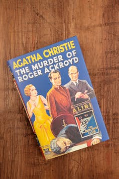 A book with the words 'Agatha Christie - The Murder of Roger Ackroyd' sits on a wooden surface.