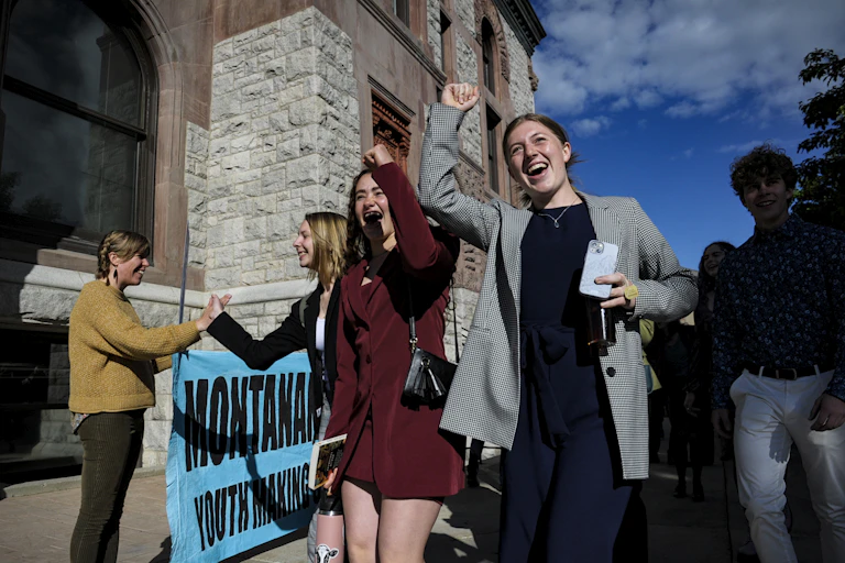 five teenagers cheer outside a stone building