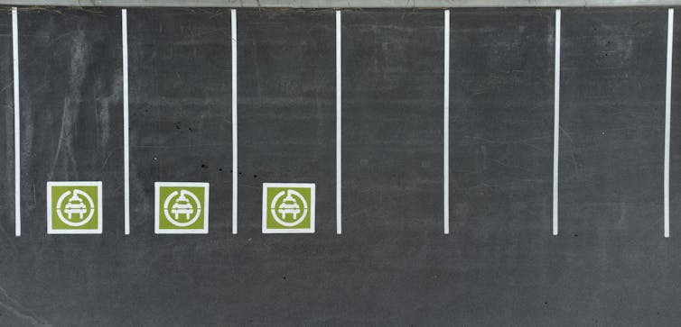 Une rangée de places de stationnement avec des zones de recharge désignées pour les véhicules électriques.
