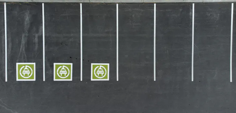 a row of parking spaces with demarcated EV charging zones.