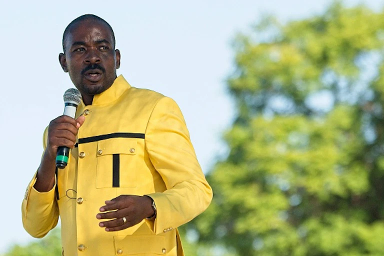 A man speaks into a microphone in his right hand.