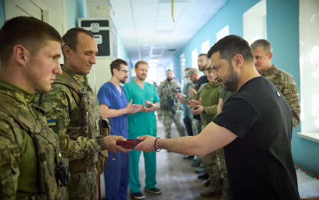 Ukraine's president, Volodymyr Zelensky hands a medal to a soldier as doctors look on, August 2023.