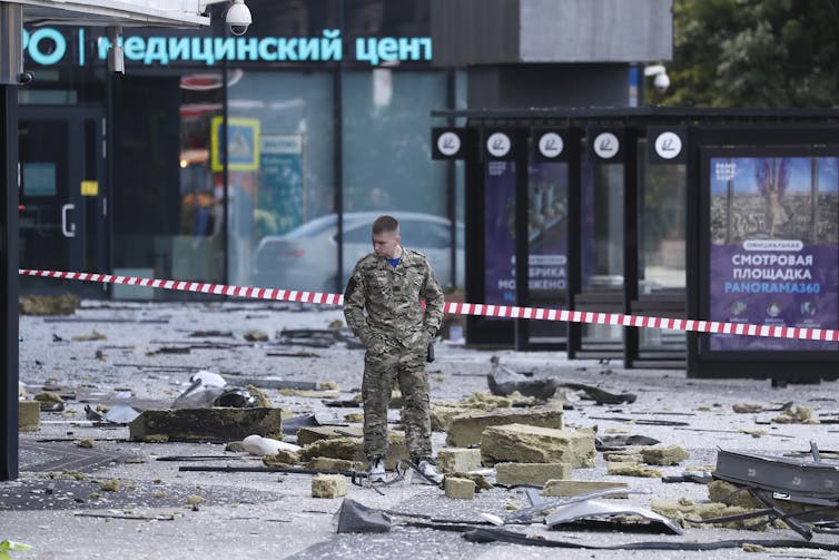 Ruský vojak stojí pod troskami po útoku dronu na centrálnu obchodnú štvrť Moskvy