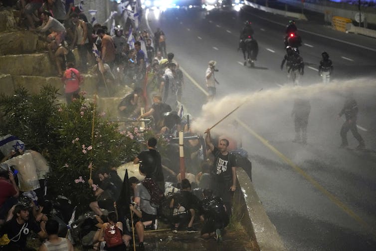 People blocking a highway being hosed by police.