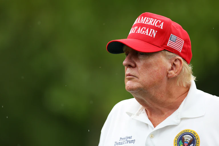 A man with reddish hair and wearing a white shirt and a red hat.