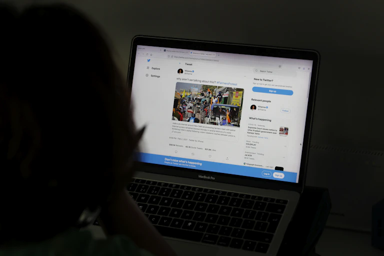 The back of a woman's head as she looks at a social media page on a laptop