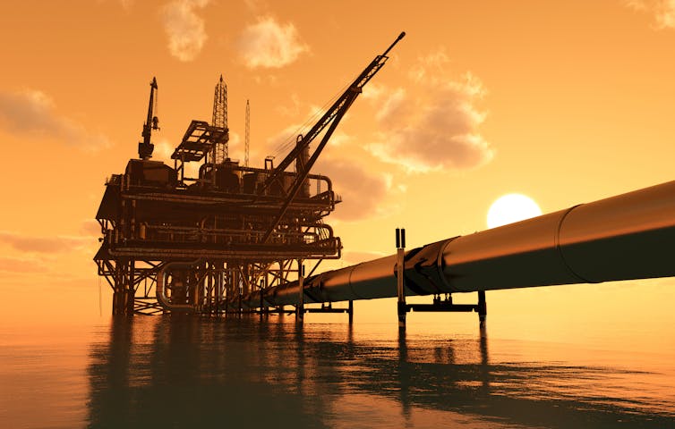 Sun sets behind an oil production platform and pipeline