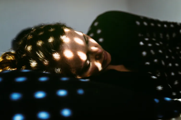 woman lies on bed in shadows