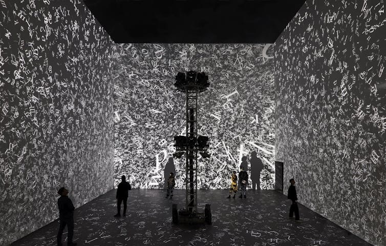 A jumble of text projected on three walls in a large room.
