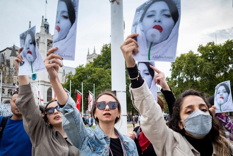 Iranian women living in exile in London hold up pictures of Mahsa Amini at the hands of Iran's morality police in September 2022.