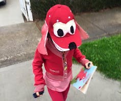 child wears reds clothes and red cap with eyes stuck on it