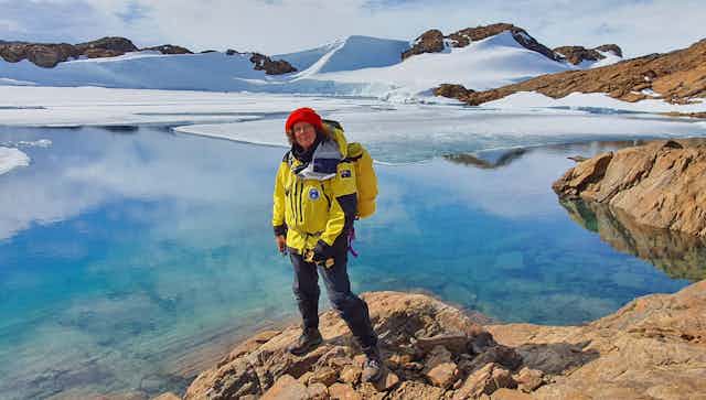 Antarctic researcher Dr Dana Bergstrom standing on the rocky shore with frozen hills in the backgrounds 