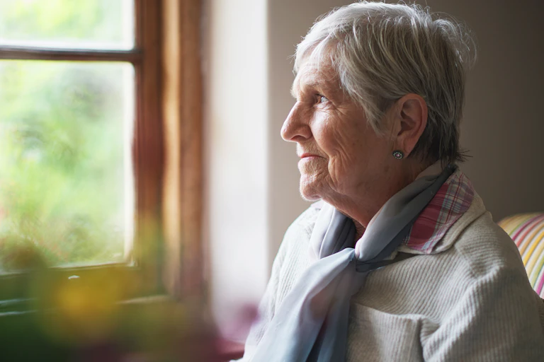 Older woman looks out the window