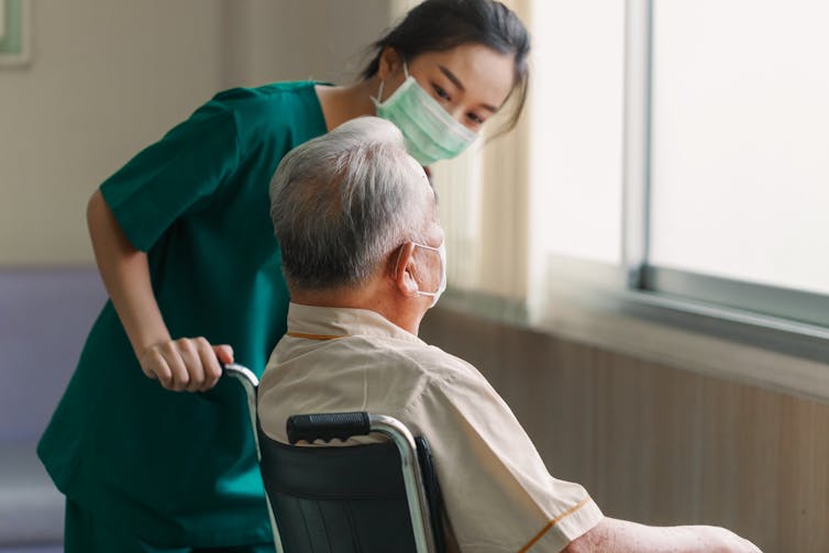 Nurse helps elderly man in a wheelchair