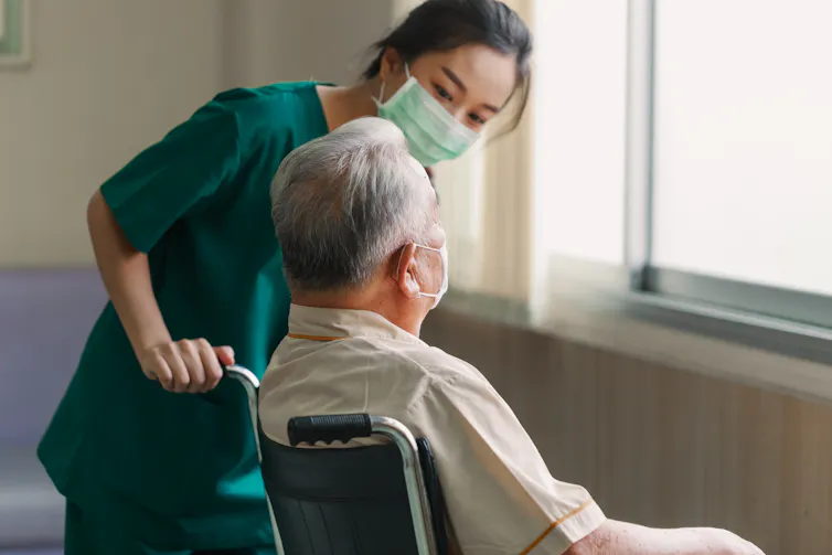 Nurse helps elderly man in a wheelchair