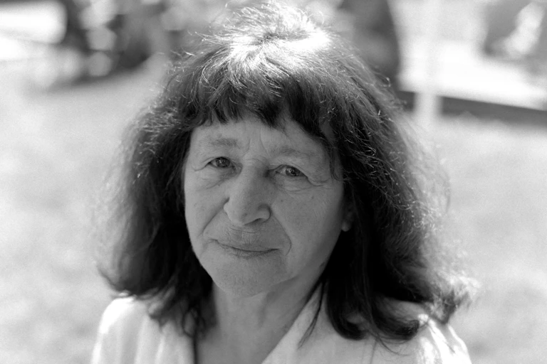 A black and white photo of a woman with dark hair. She is looking into the camera.