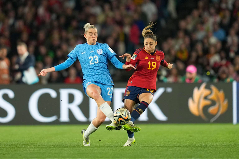 Two female football players battle for the ball