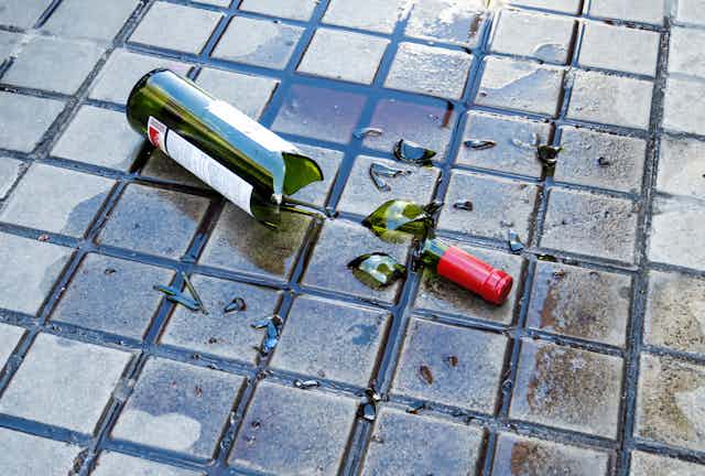 A broken wine bottle on pavement. 