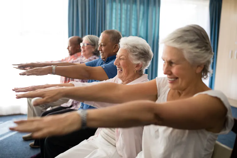Cinq personnes âgées assises, faisant des exercices avec les bras