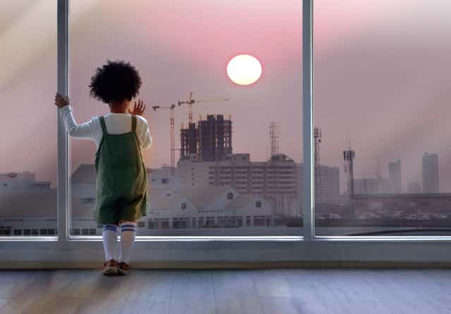 Small child looking out of window at tower cranes