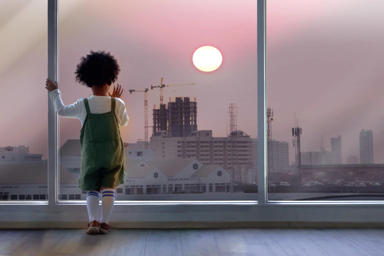 Small child looking out of window at tower cranes