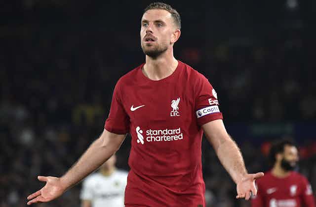 A man in a red football outfit on a pitch.