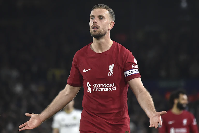 A man in a red football outfit on a pitch.