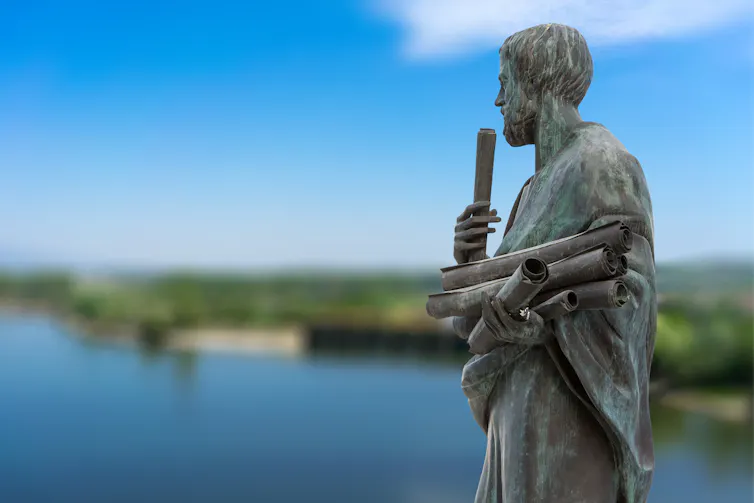 A stone statue with a body of water behind it.