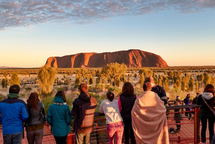 Tourists watch the sun rise over Uluru.