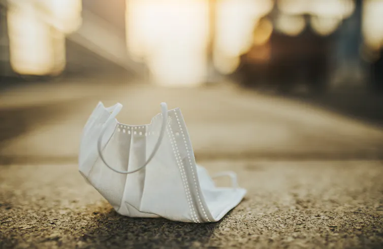 A used surgical face mask lying on the ground