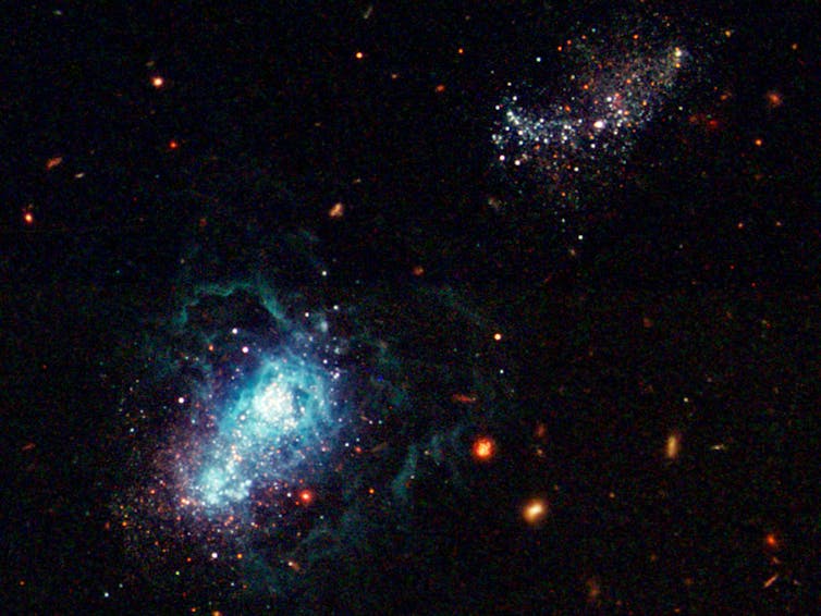 Two large groups of bright dots and colored swirls, mostly blue, on a black background.