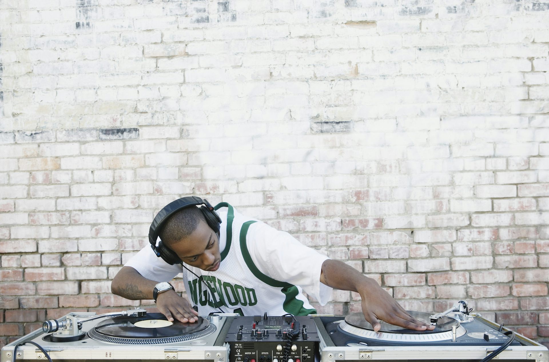 A young male deejay manipulates vinyl records on two turntables.
