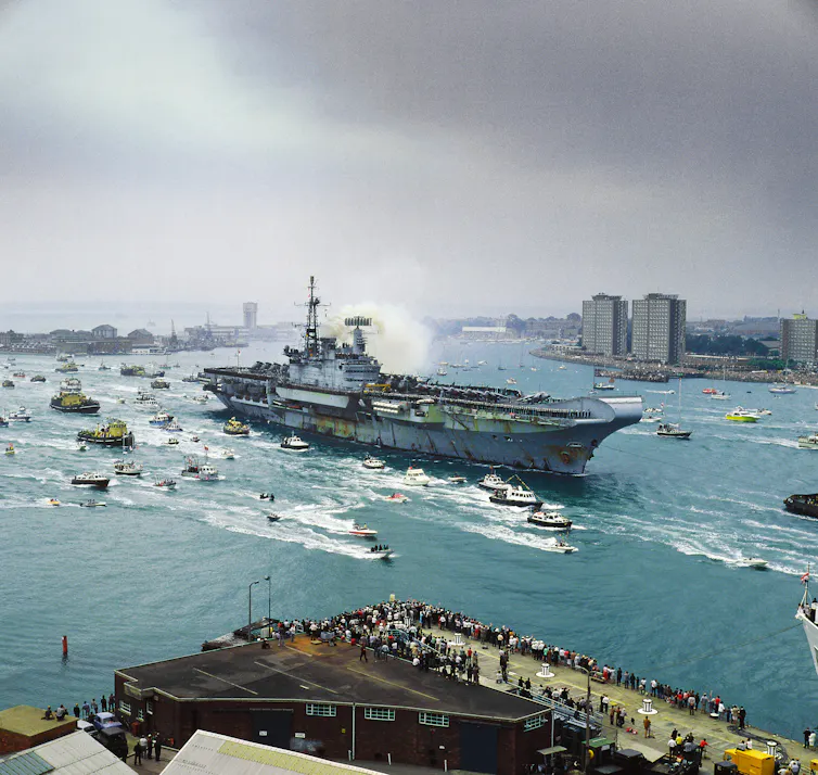 A ship in port with many small ships.