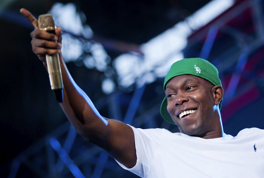 Dizzee on stage with a mic and green hat