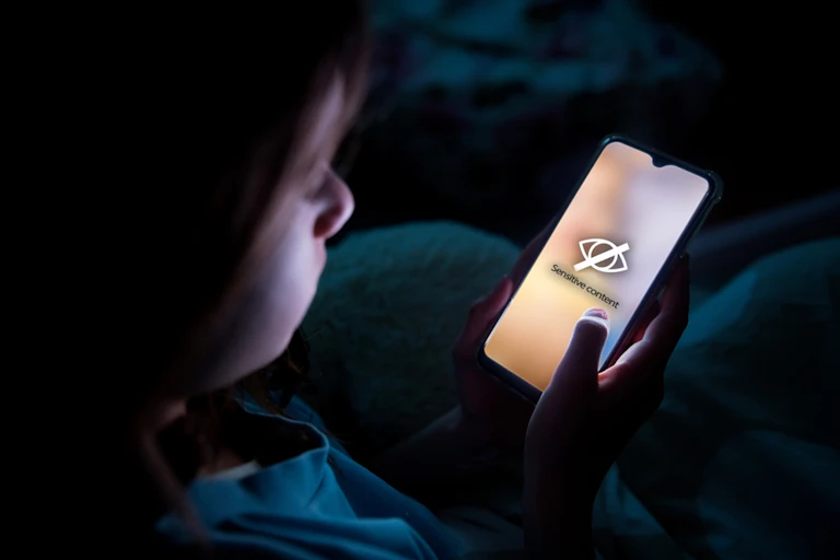 Jeune regardant du contenu interdit sur un smarphone, la nuit dans sa chambre