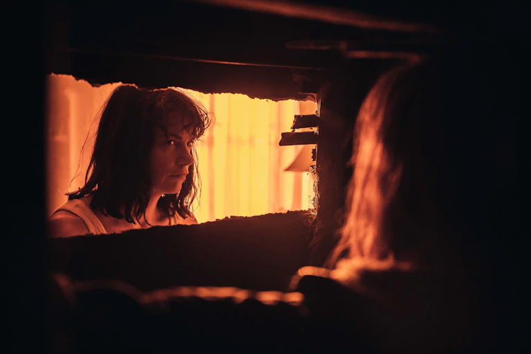 Ruth Wilson looking through hole in the wall.