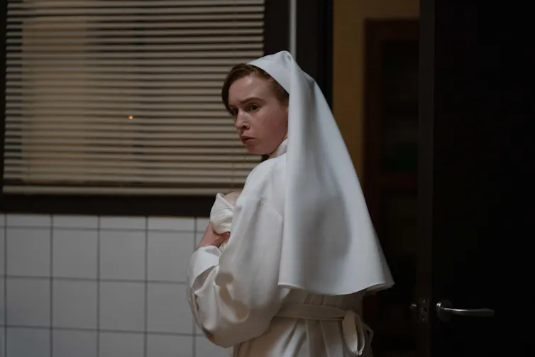 A nun in white habit holding a baby.