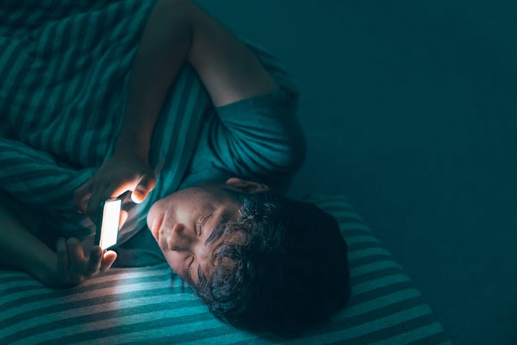 Teenage boy in bed looking at phone