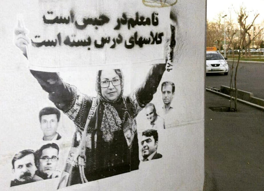 A mural on a wall shows a woman holding up a sign with Arabic writing.
