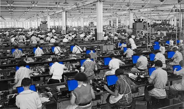 historic black and white photo of rows of women working at benches with blue computer screens in front of them
