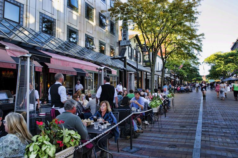 A downtown city street with people eating outside at a cafe.